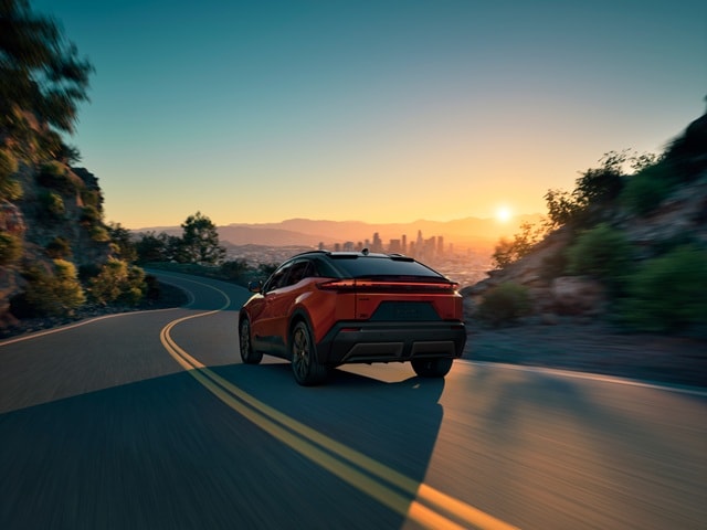 Orange Toyota C-HR XSE driving away on a winding road