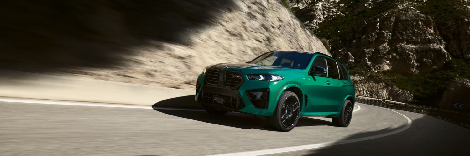 bright green BMW X5 M SUV driving up a winding mountain road
