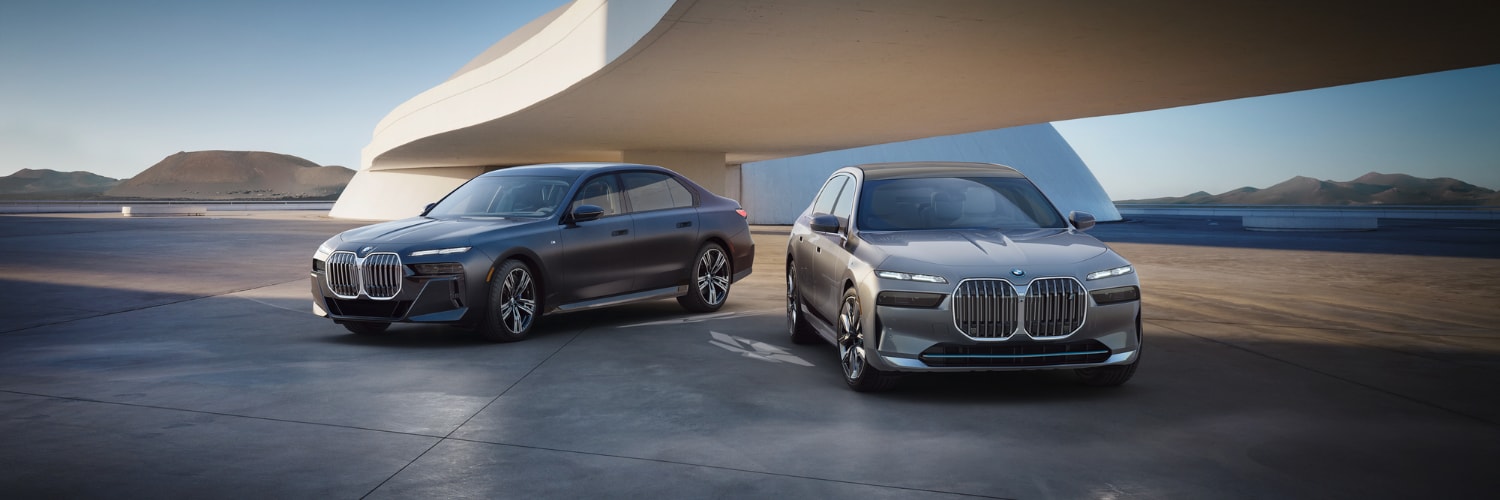 two new BMW 7 Series sedans parked outside with mountains in the background