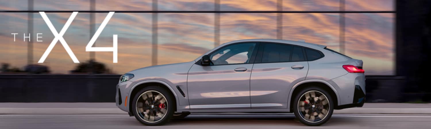 side view of a silver BMW X4 SUV in motion