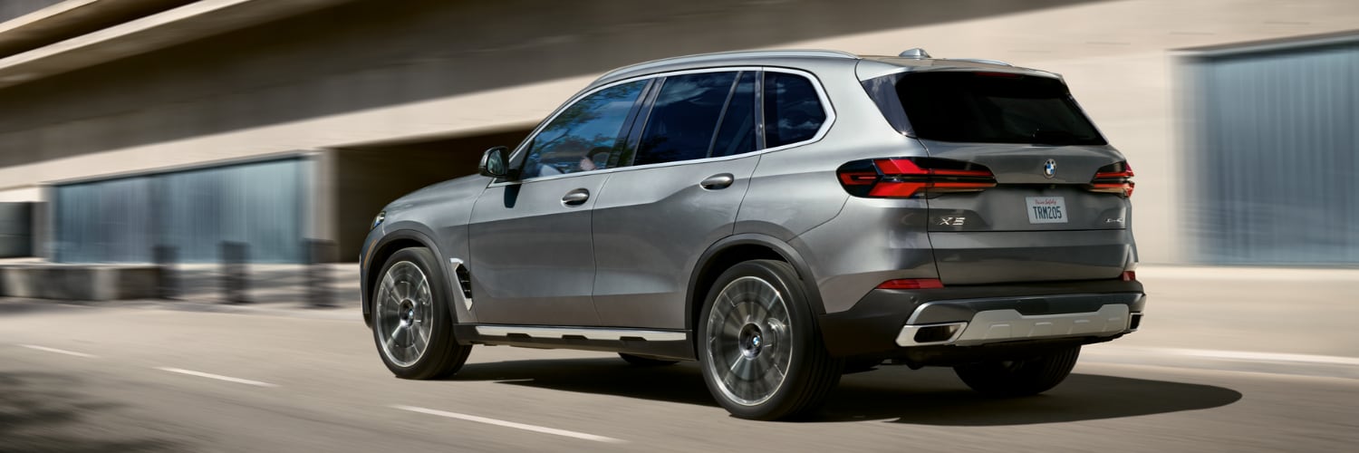 silver BMW X5 driving along a city road