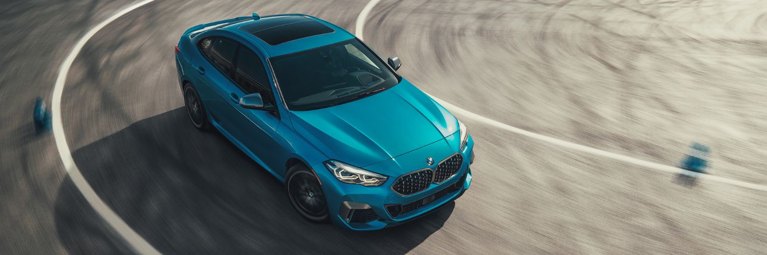 teal blue BMW M235i turning on an asphalt driving course