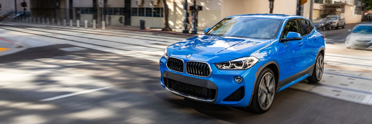 blue BMW X2 SUV driving through and intersection