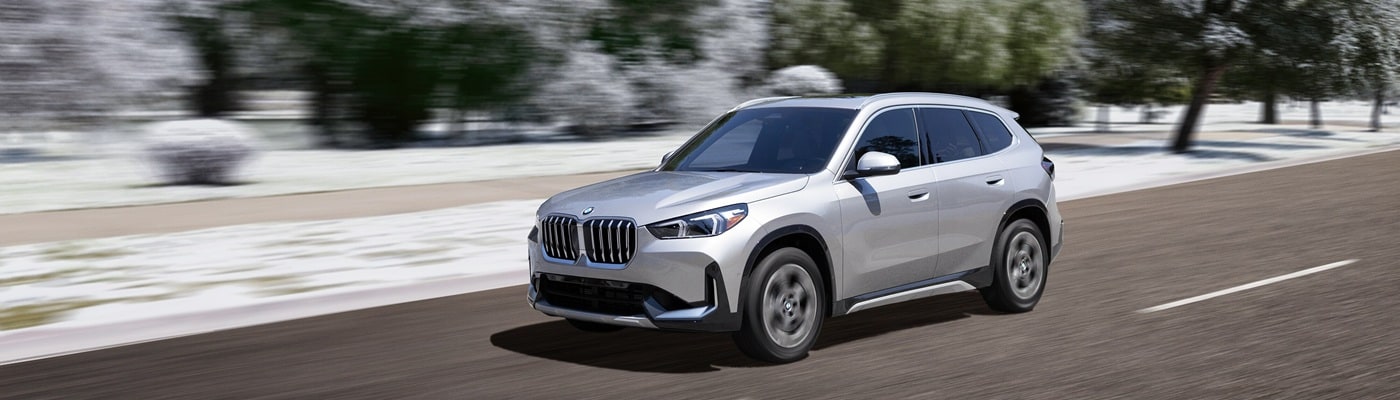 Silver BMW X1 driving on a road during the winter