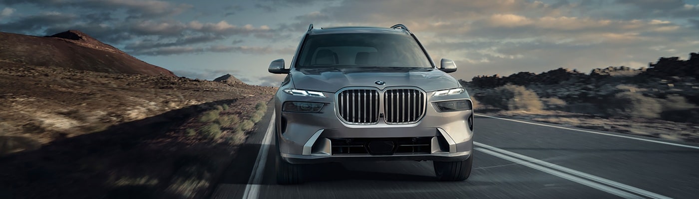 Grey BMW X7 driving on a road in the desert