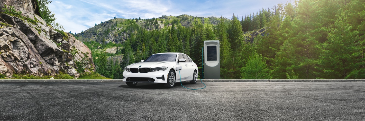 white BMW 330e sedan charing at a scenic mountain charging station
