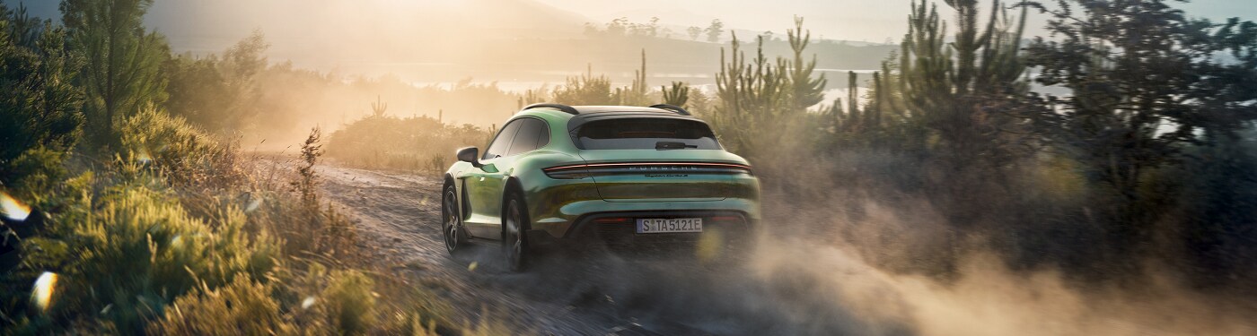 Green Porsche Taycan Cross Turismo Turbo S driving on a dirt road