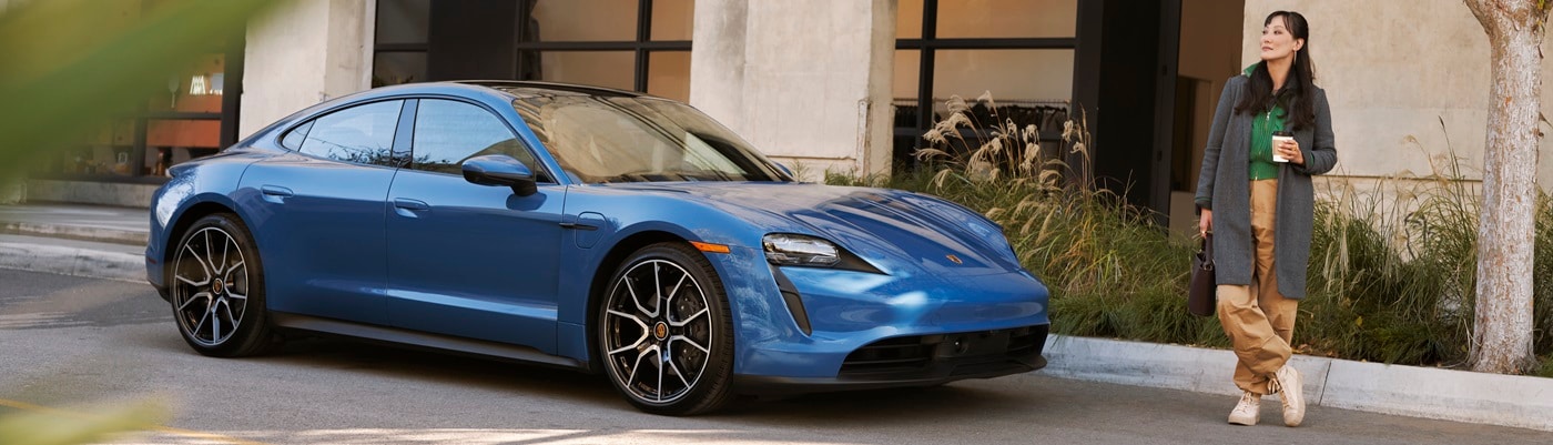 Porsche Taycan Blue Taycan parked by a person drinking a coffee