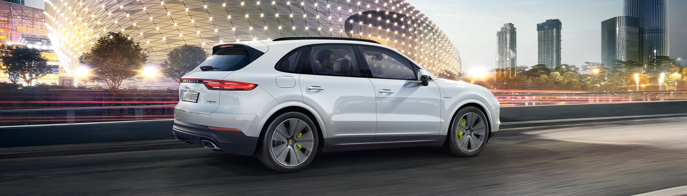 Cayenne E-Hybrid driving on a city street at dusk