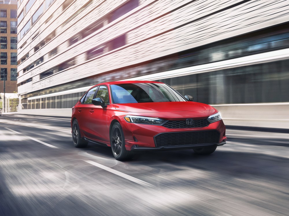 Red Honda Civic Hybrid driving on a city street