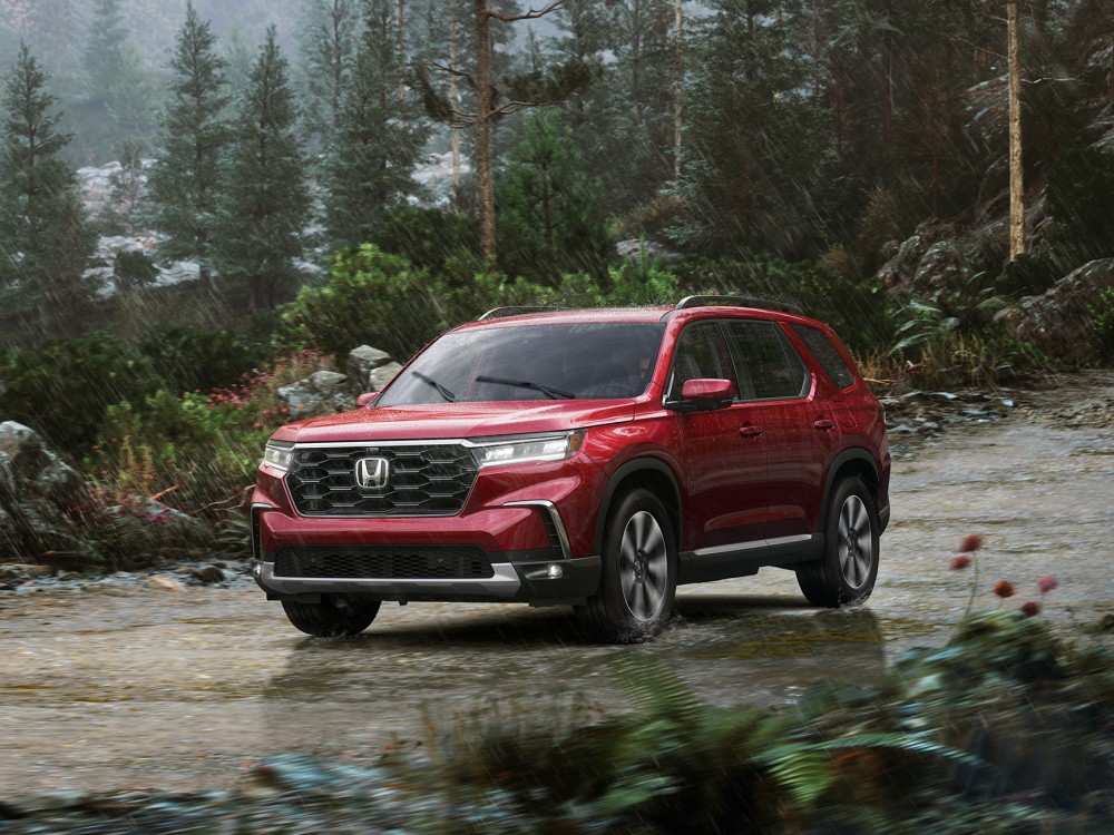 Red Honda Pilot driving on a winding forest road