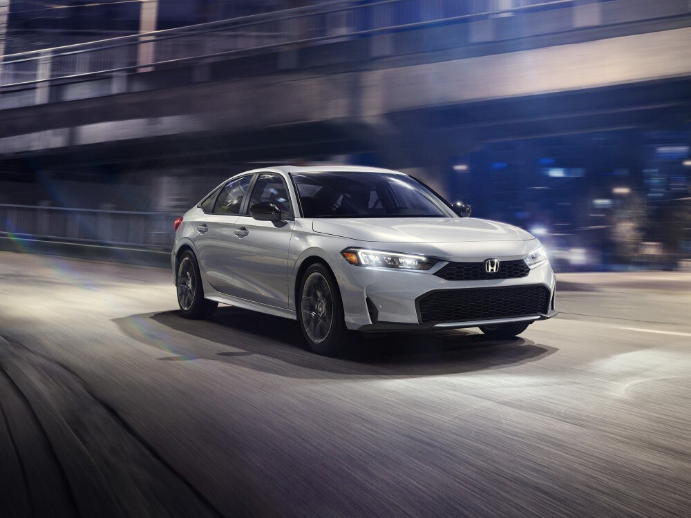 White Honda Civic driving on a city street at night