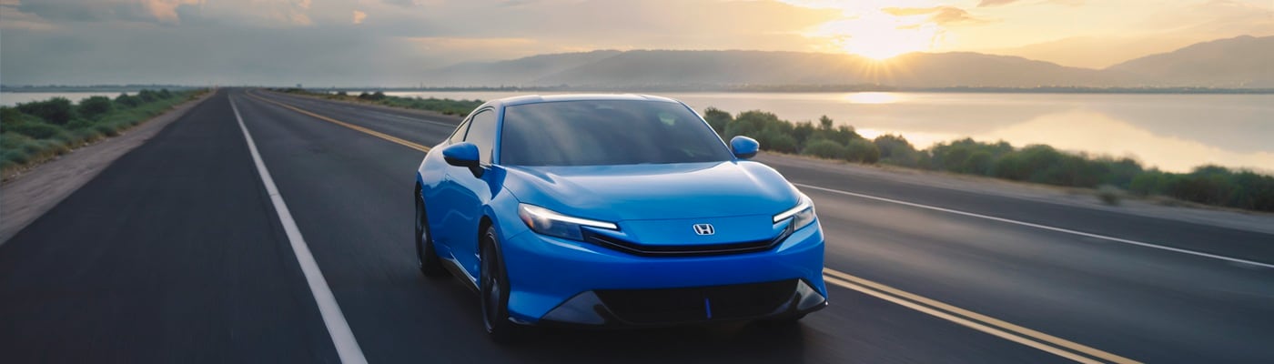 Blue Honda Prelude driving on a road near a lake