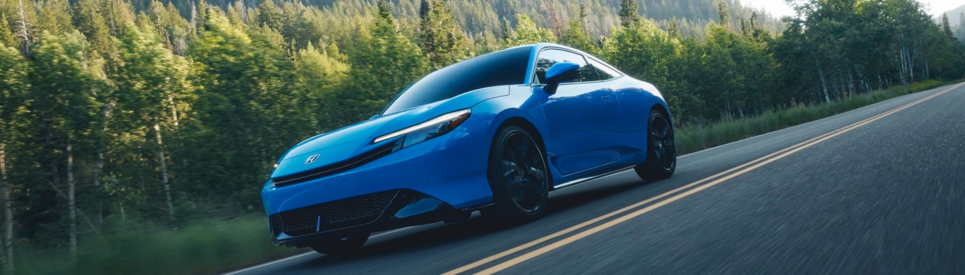 Blue Honda Prelude driving on a road in the woods