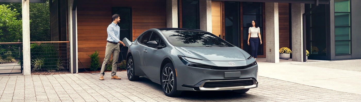 Grey Toyota Prius PHEV XSE Premium charging by a modern house