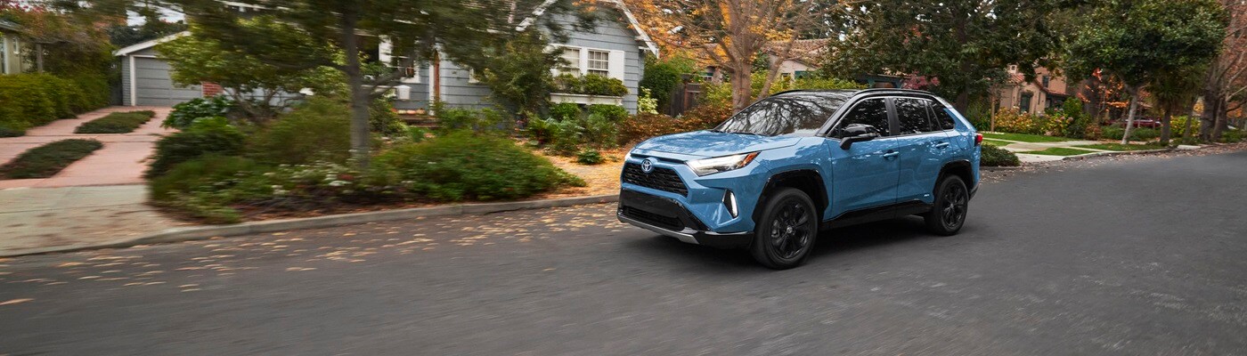 Blue Toyota RAV4 Hybrid XSE driving through the suburbs