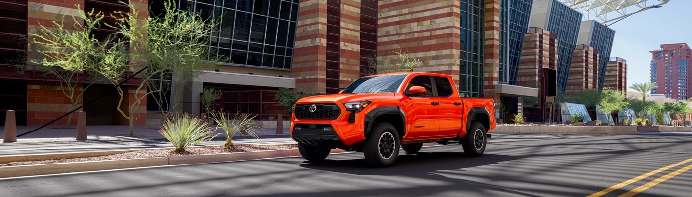 Orange Toyota Tacoma TRD Off Road driving in a desert city