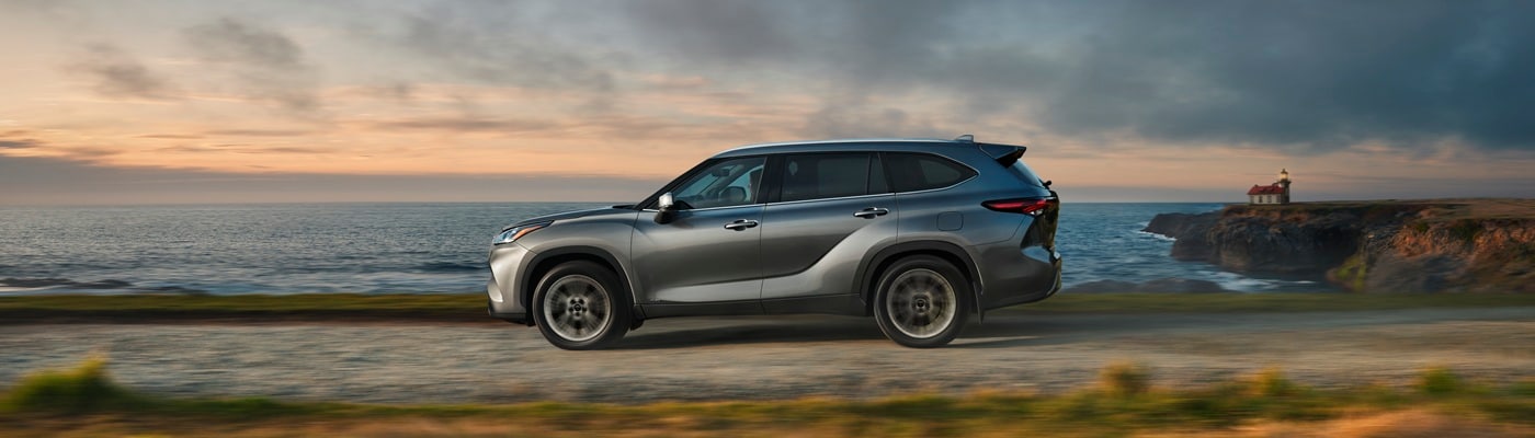 Grey Toyota Highlander Hybrid Limited driving on a road along the coast