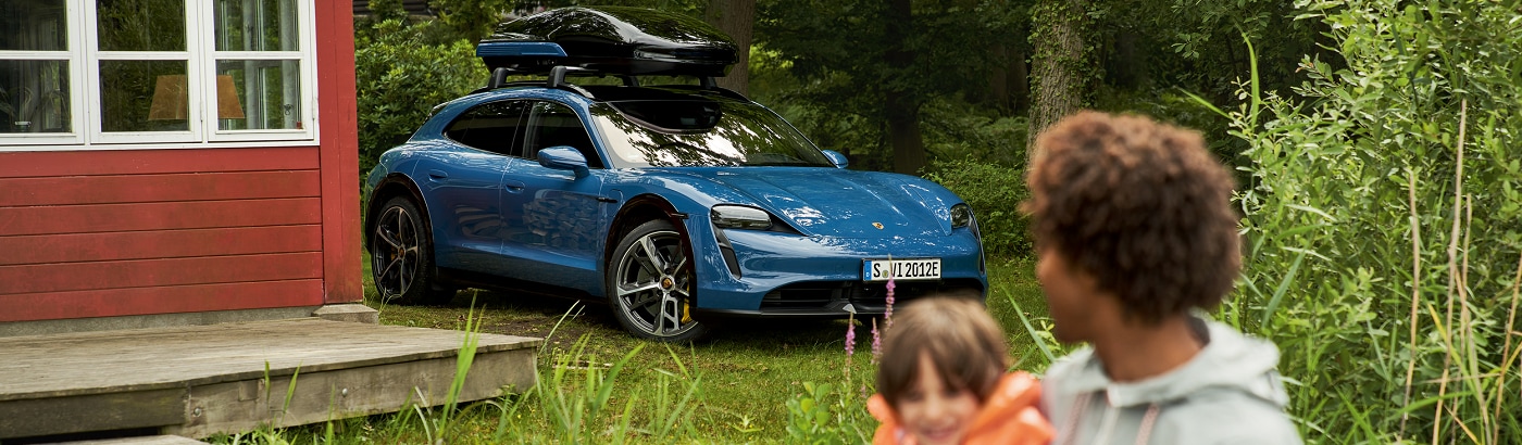 Porsche Taycan Cross Turismo Turbo S parked by a lakeside cabin