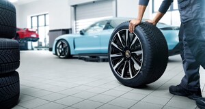 Porsche Tires Service Tech rolling a tire towards a Porsche vehicle