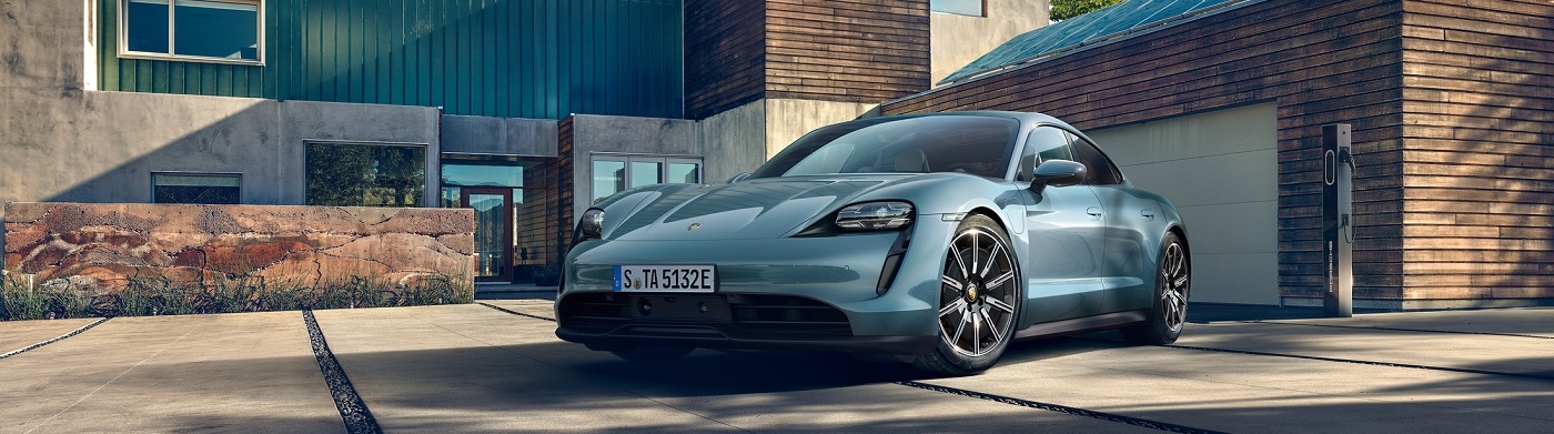 Lite Blue Porsche Taycan parked in the driveway of a modern house