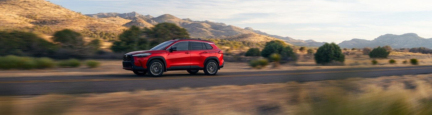 Red Toyota Corolla Cross XLE driving on a road in the desert