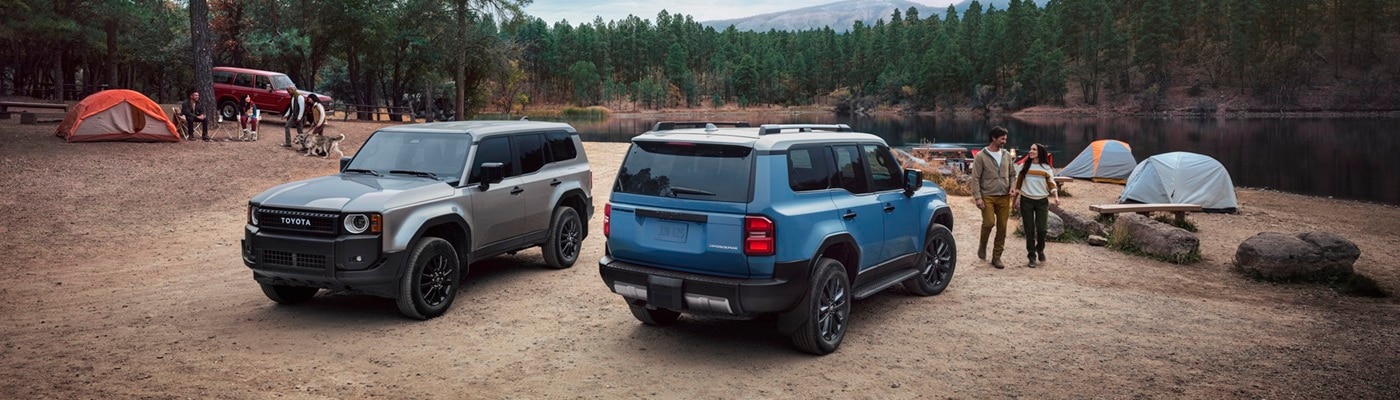 Two Toyota Land Cruisers parked by a lake in the woods