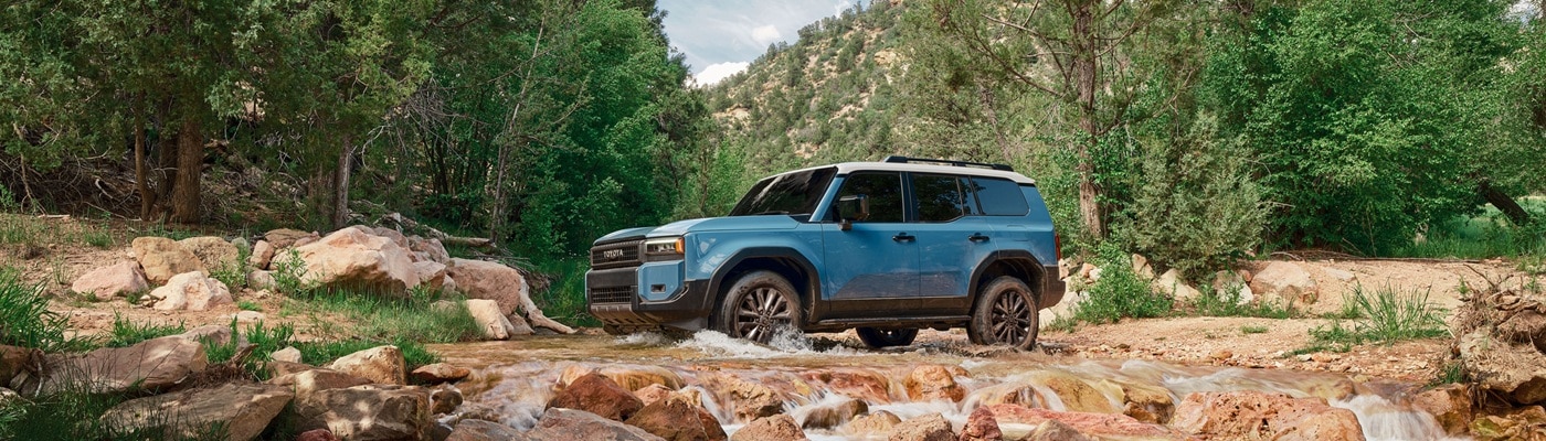 Blue Toyota Land Cruisers fording a river