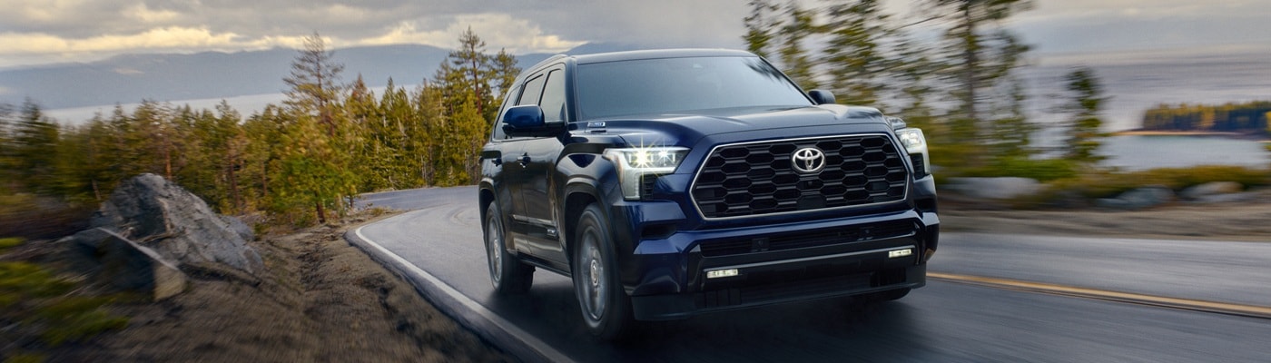 Blue Toyota Sequoia Platinum driving on a road in the forest