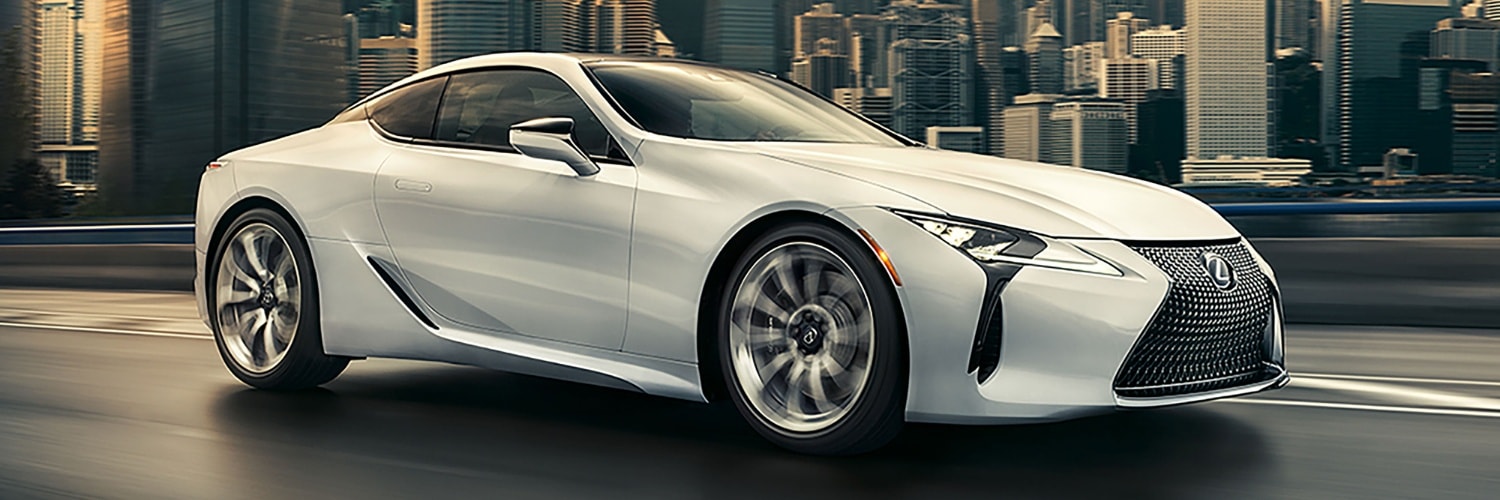 White Lexus LC 500 Coupe driving away in a city