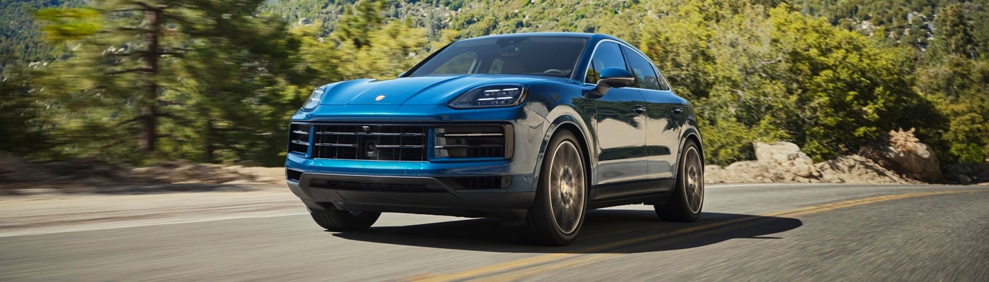 Blue Cayenne Coupe driving on a road in the forest