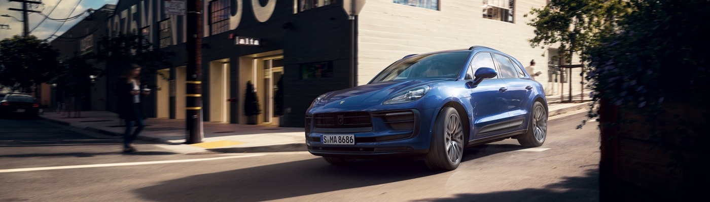 Blue Porsche Macan driving on a city street