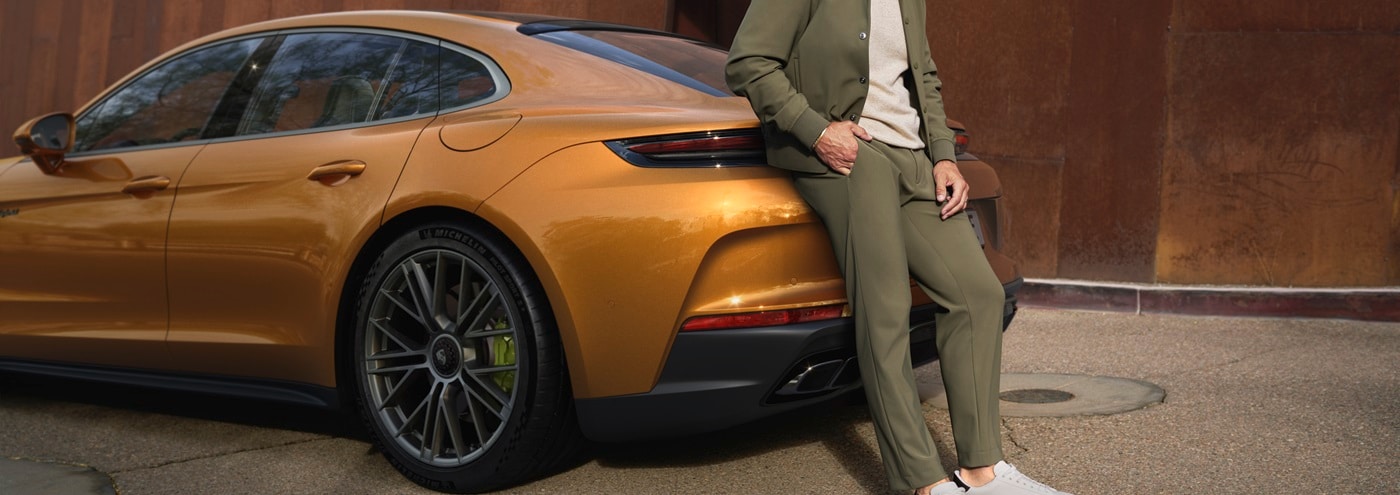 Orange Panamera E-Hybrid parked with a person leaning on the car