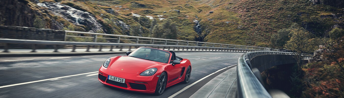 red Porsche 718 Boxster T convertible driving on a misty mountain road