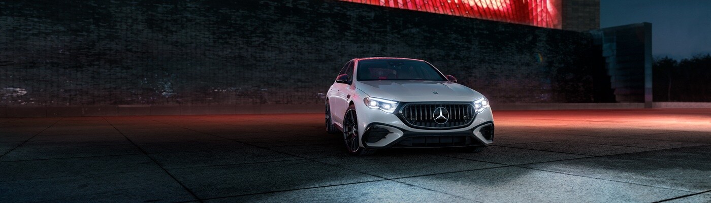 White Mercedes-Benz AMG E-Class sedan parked in front of a building at night