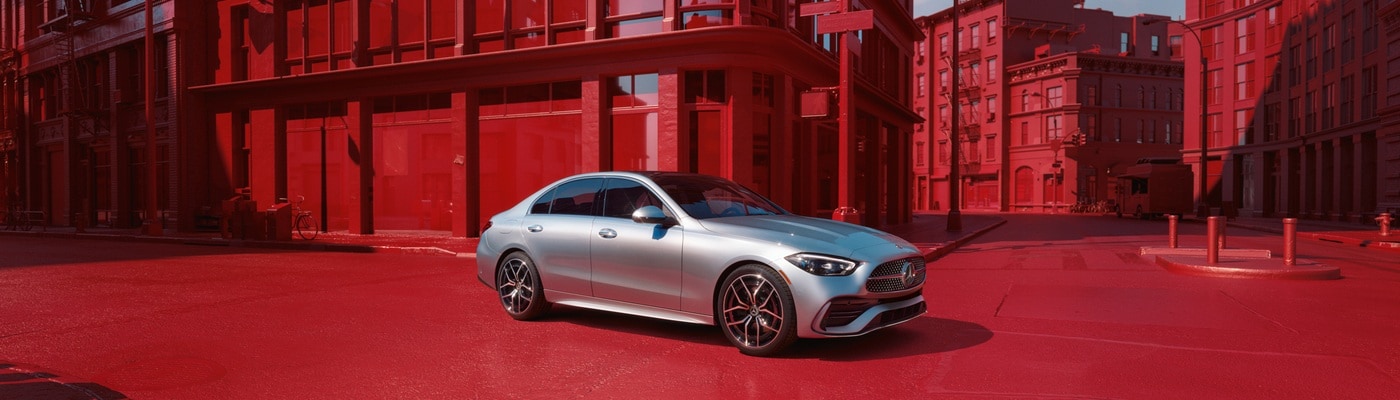 Silver Mercedes-Benz AMG C 43 sedan driving in a red cityscape