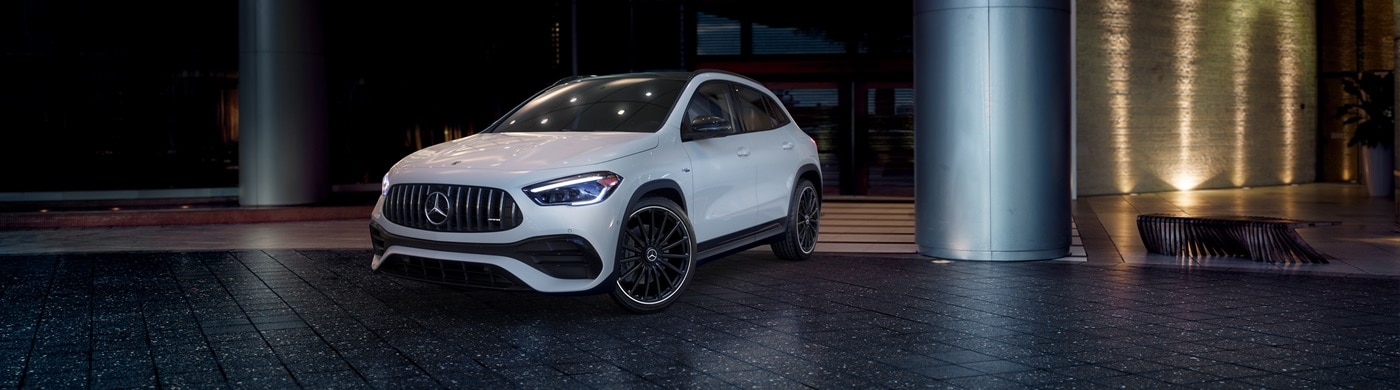White Mercedes-Benz AMG GLA 35 parked in front of a building in a city