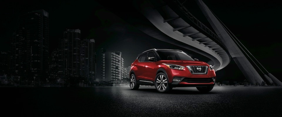 Red Nissan Kicks in a Dark City A red 2018 Nissan Kicks parked under a bridge in the bright part of a dark city