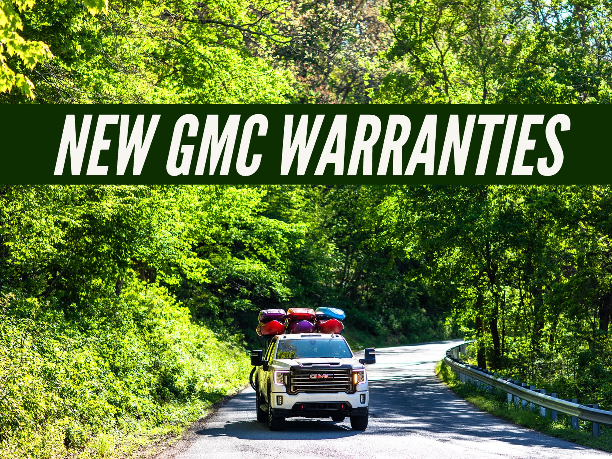 "New GMC Warranties" on Photo with new GMC Sierra At4 driving down wooded road