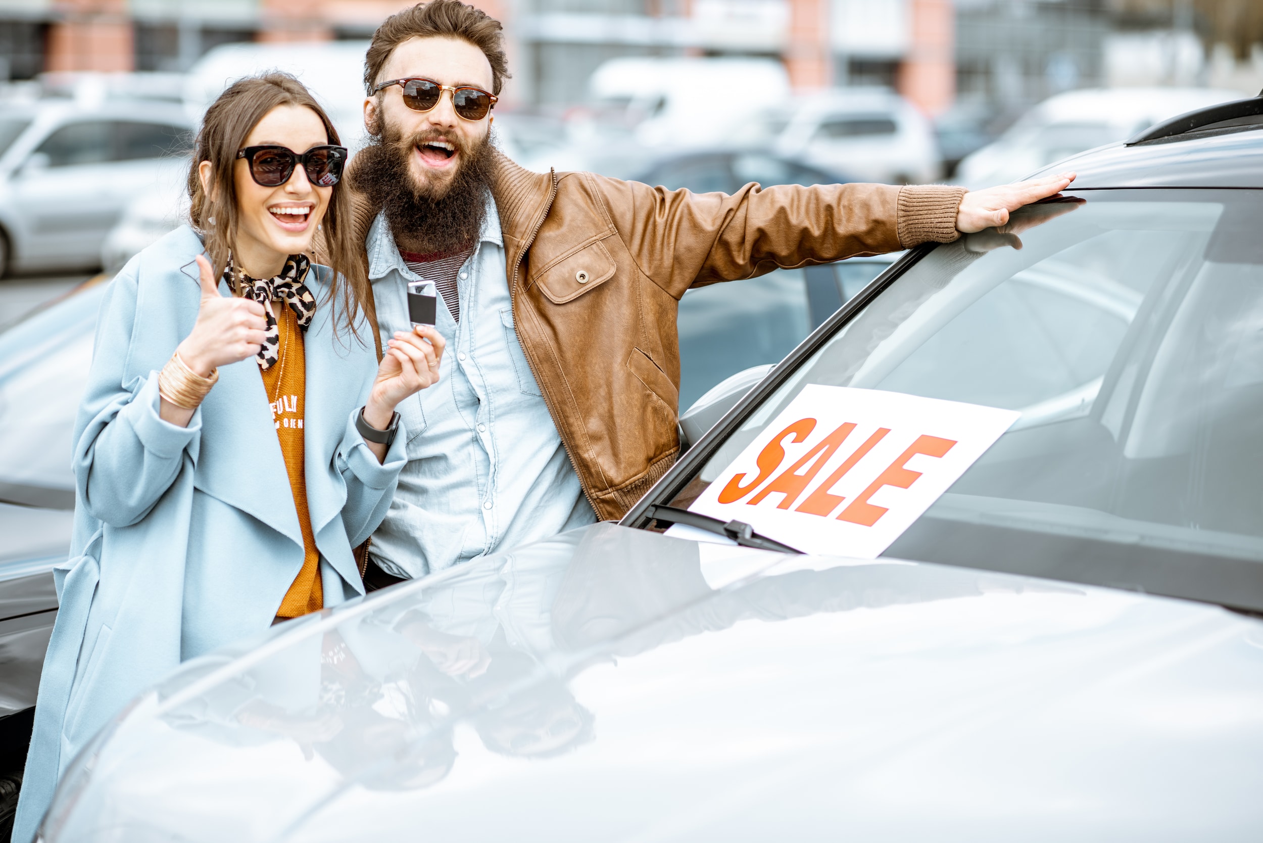 Excited couple next to vehicle holding keys
