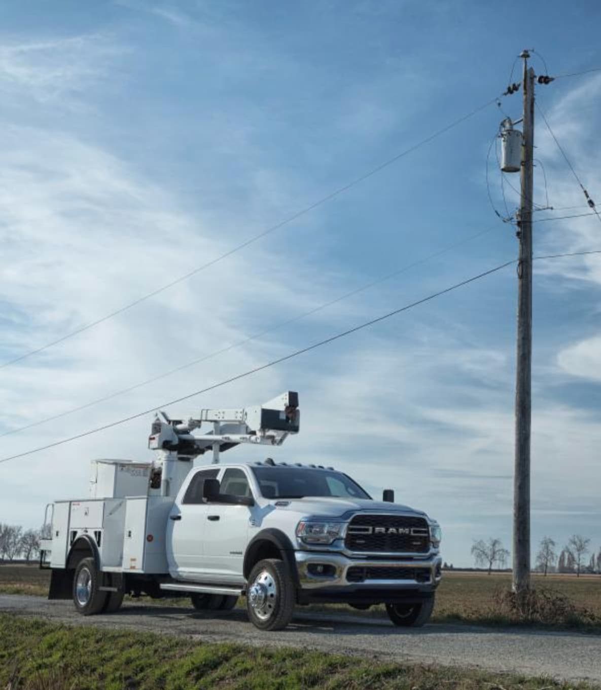 Parked Ram truck with lifting mechanism upfit next to phone pole