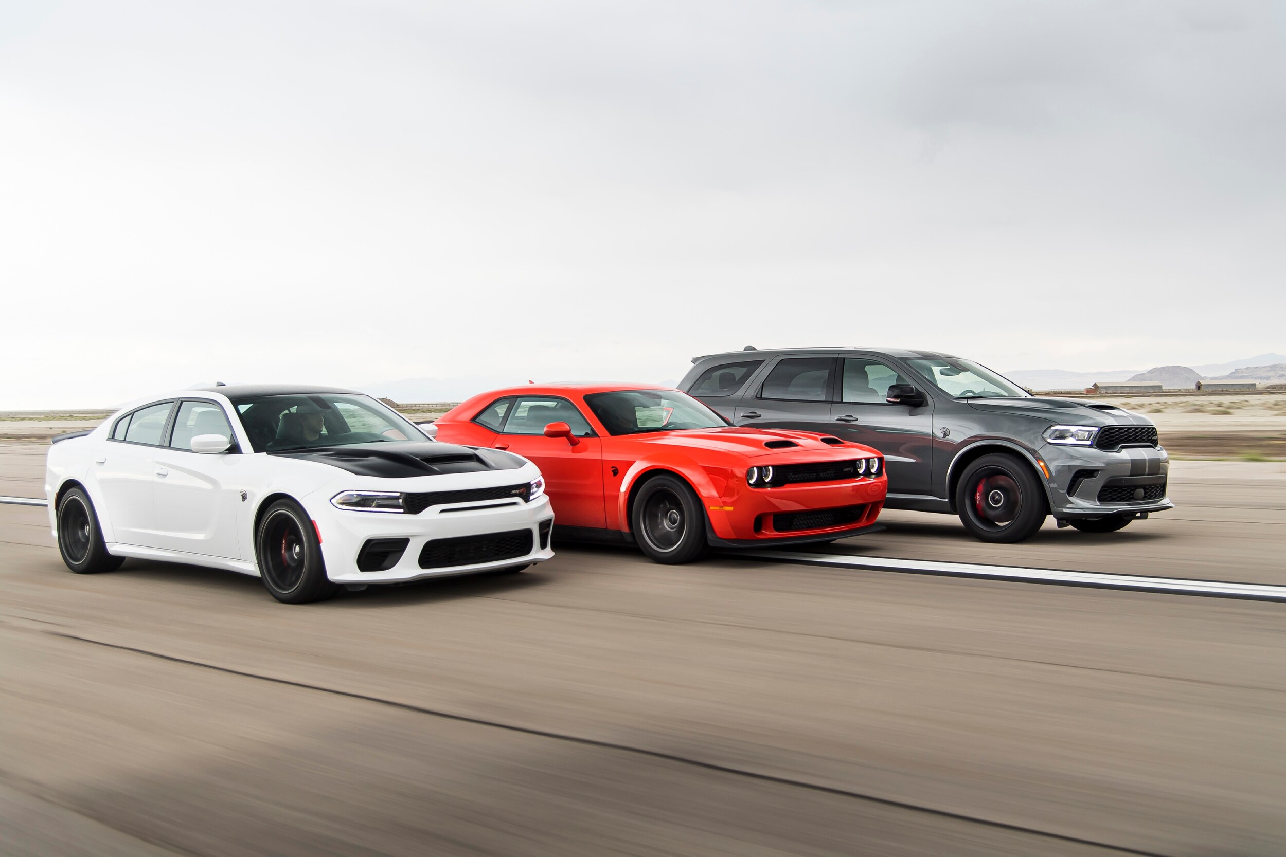 White Dodge Charger, Red Dodge Challenger, Dark Grey Dodge Durango driving next to each other