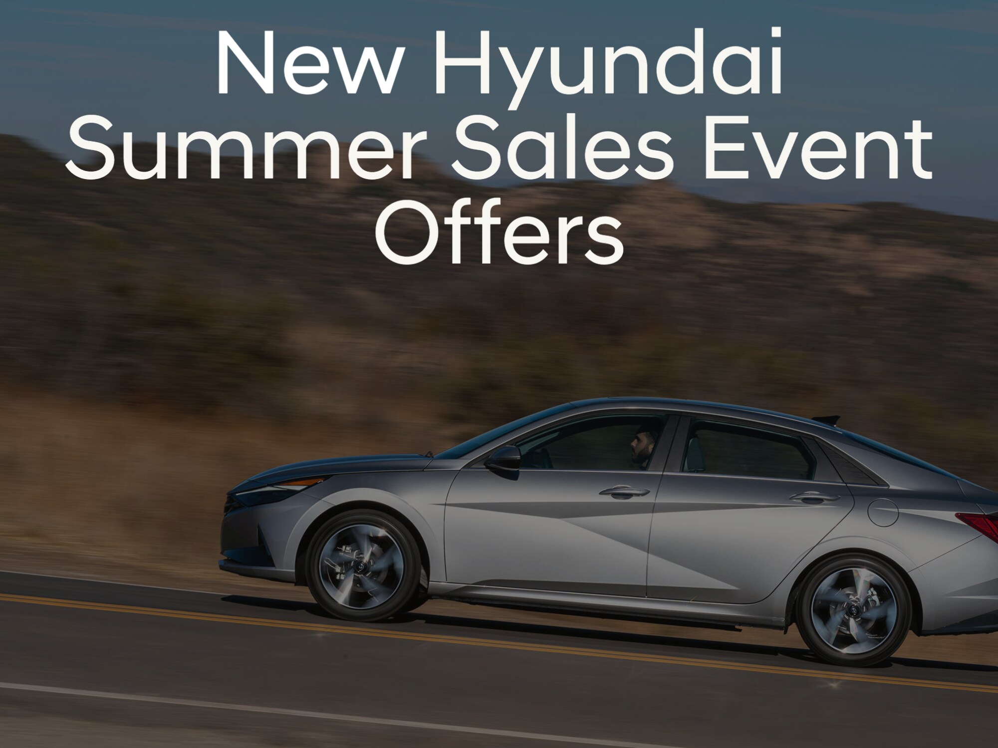 Side View of new Silver Hyundai Elantra driving uphill with words "New Hyundai Summer Sales Event Offers" in white font at the top of photo