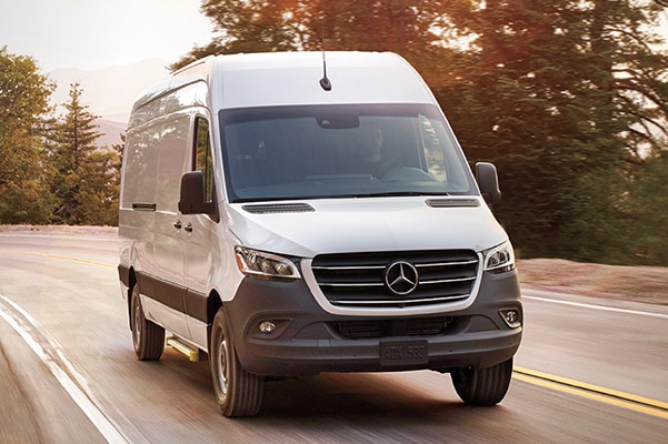 2021 Sprinter Van driving diwn a road with trees in the background