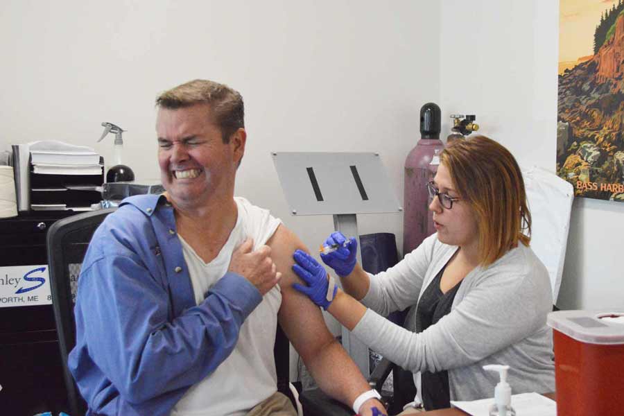 Mark makes a big show of wincing during his flu shot, because he is a big ham