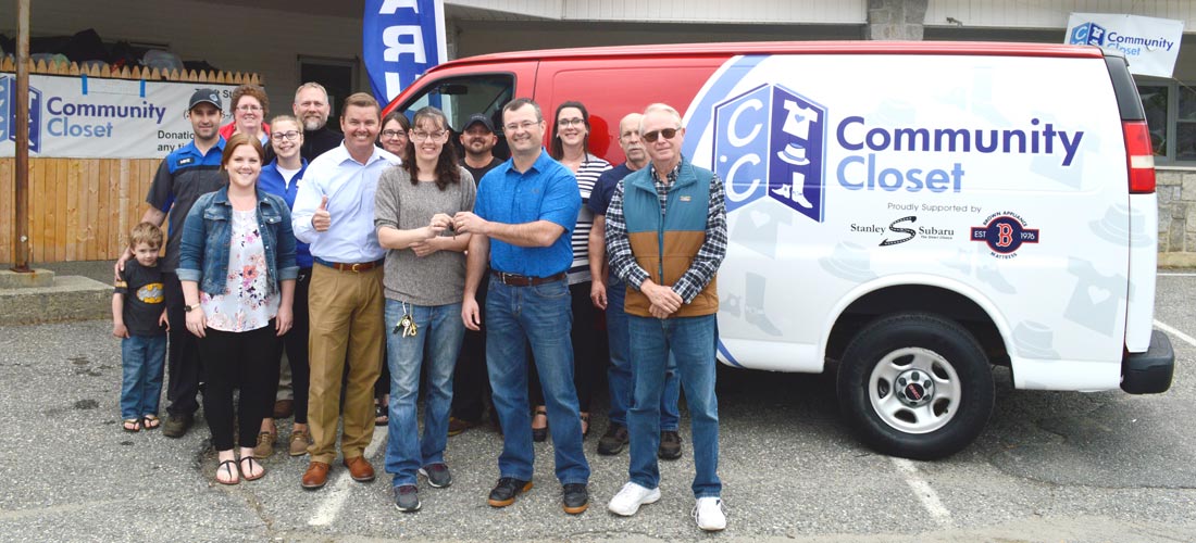 A happy group of people standing around a van