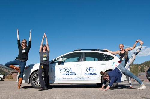 Team posing in front of an Impreza with Yoga Journal Conference decals