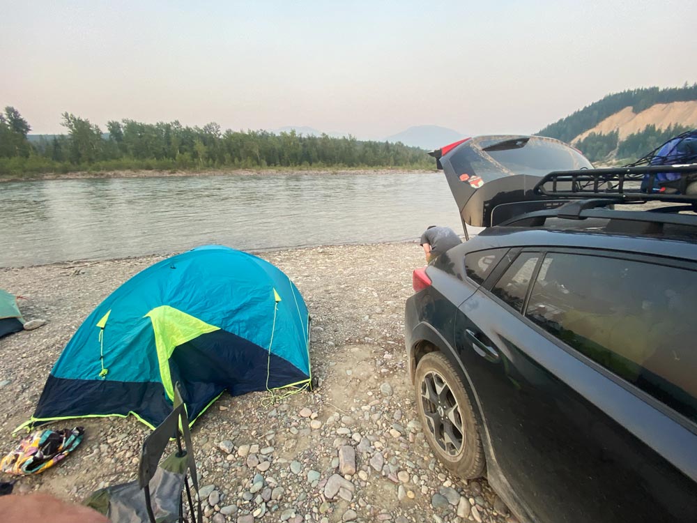 Crosstrek at the edge of a lake with a tent set up nearby