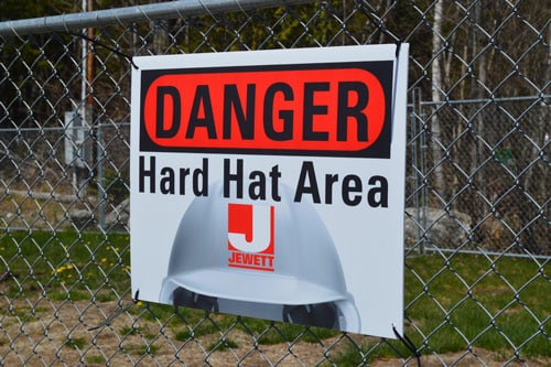 Hard Hat Area sign on a fence by our annex