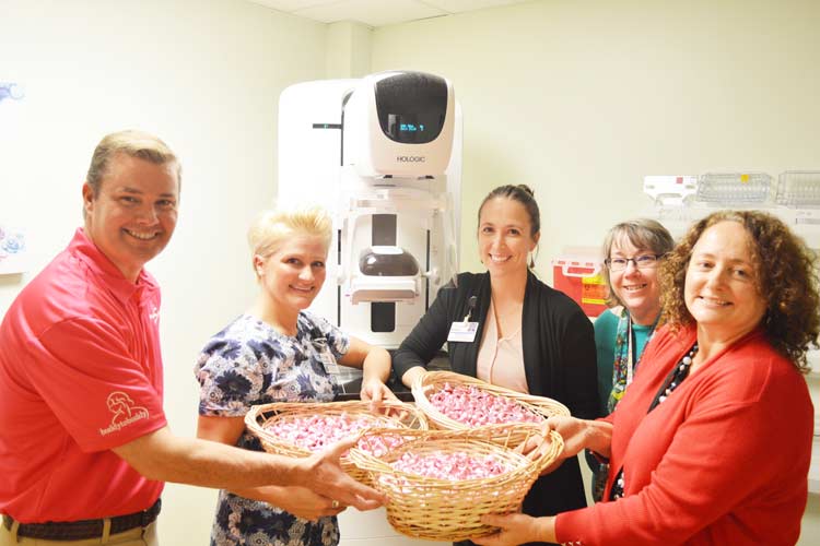 Stanley Subaru and Breast Health Clinic staff in front of the 3-D mammography machine, holding baskets of pink-wrapped Hershey Kisses
